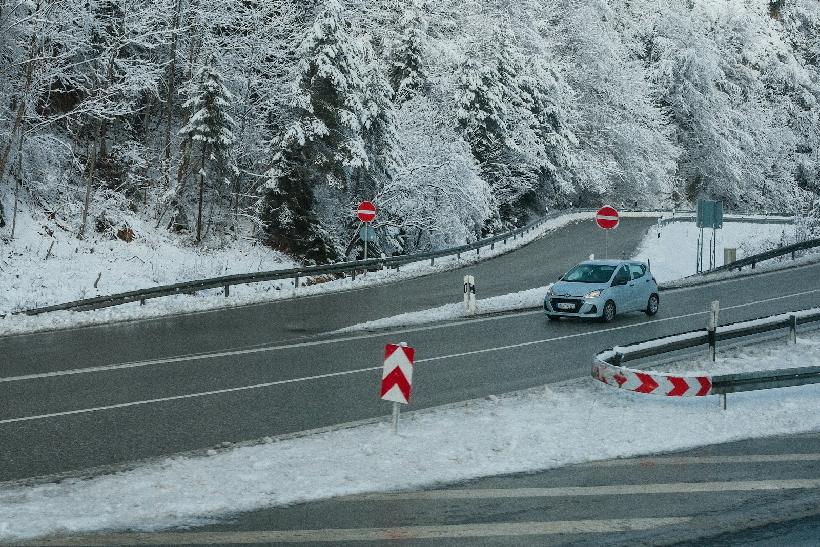 A car is driving down a snowy road