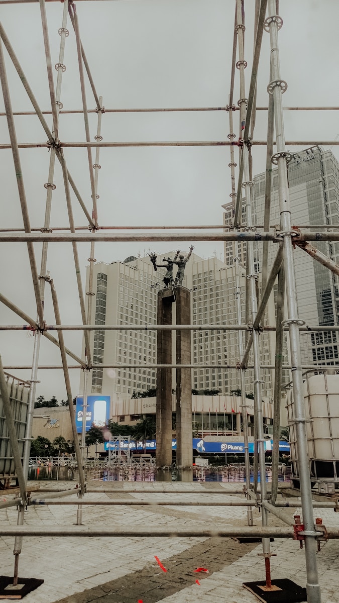 Scaffolding surrounds a statue in a city square.